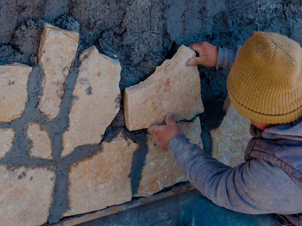 Pracovník přikládá kamenný obklad na fasádu